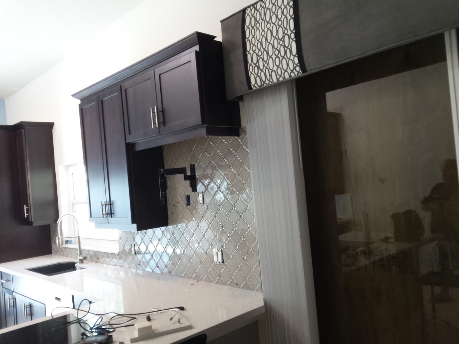 Arabesque tile backsplash behind the range, cut in around the pot filler against dark cabinets