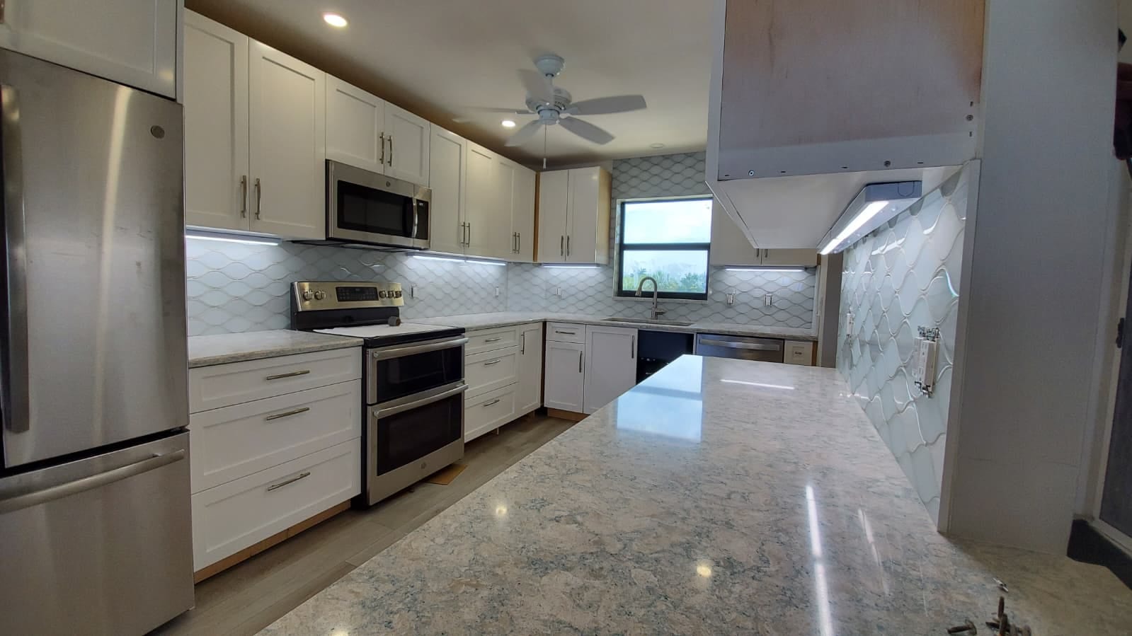 Full-height arabesque tile backsplash in a white kitchen, carried around onto the range wall
