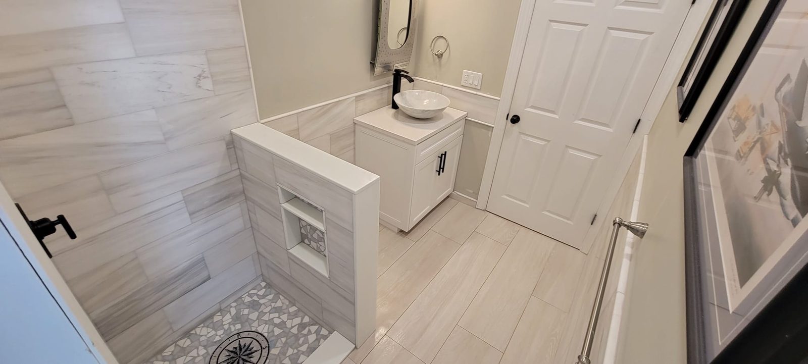 Walk-in shower with a tiled half wall and a patterned mosaic floor