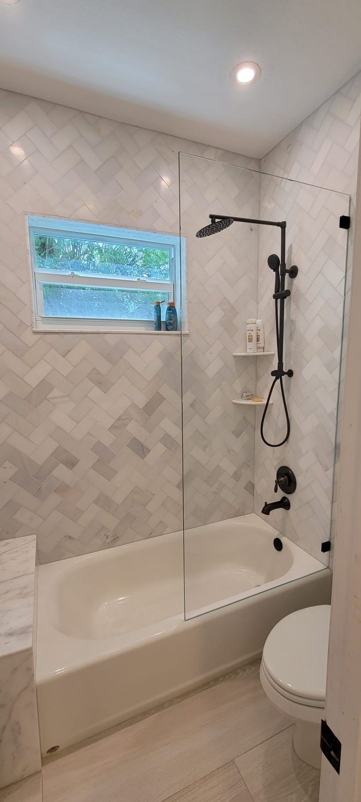 Herringbone marble tub surround built around a window