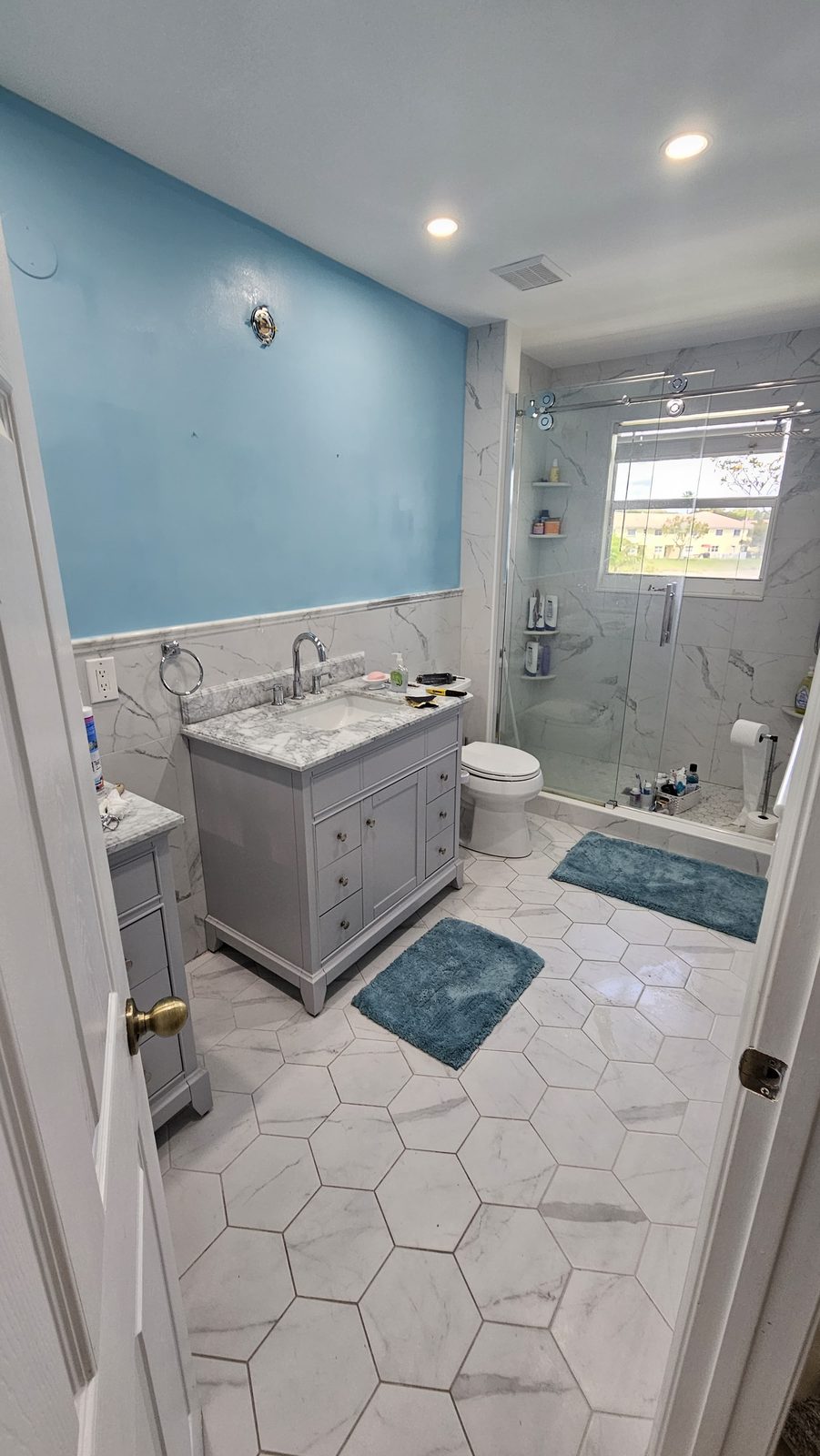 Full bathroom in hexagon marble floor tile with marble wainscot and a glass shower