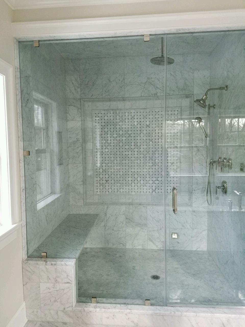 Marble shower with a basketweave mosaic panel, built-in bench and glass enclosure