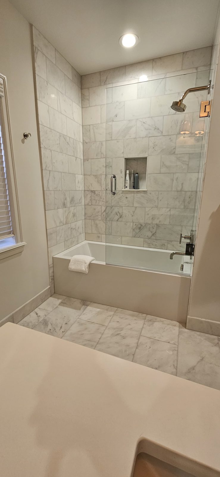 Marble tub alcove with a recessed shampoo niche and marble floor