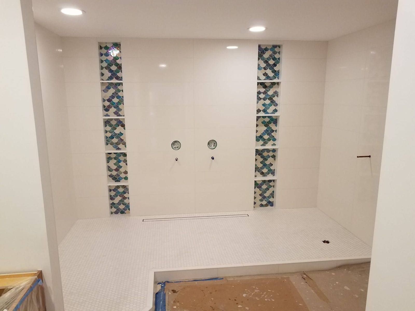 Finished double shower with vertical glass mosaic inlays and a linear drain