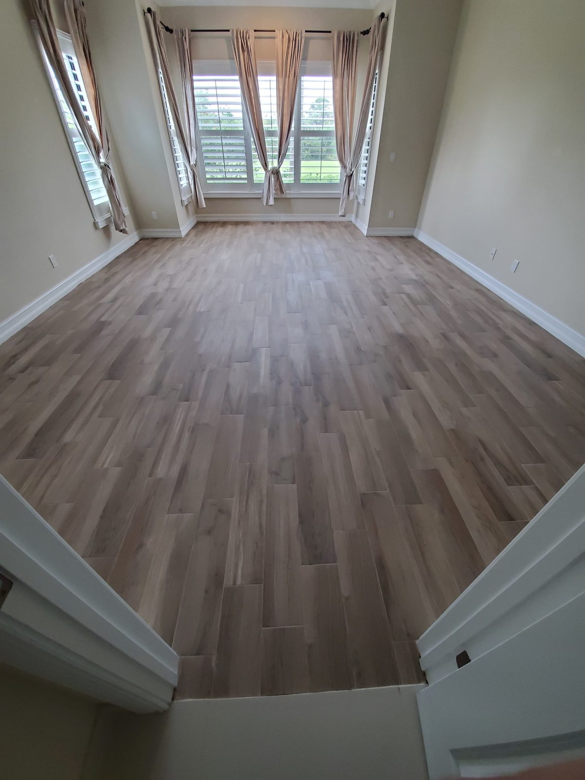 Wood-look porcelain plank floor laid through a bedroom bay