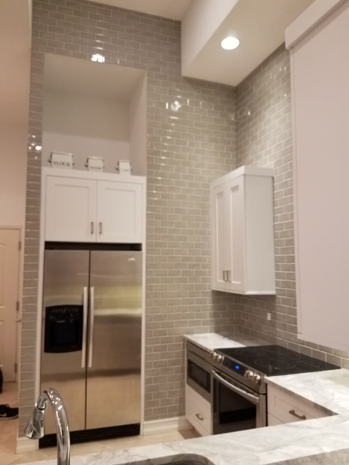 Grey subway backsplash run to the ceiling around a tiled fridge alcove