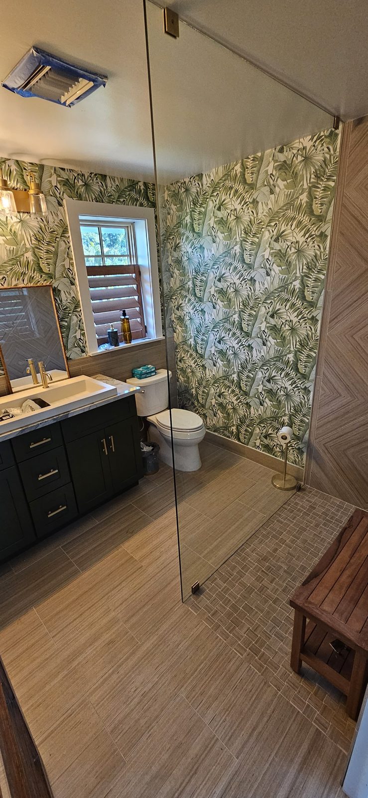 Wood-look tile floor and walk-in shower behind a frameless glass panel